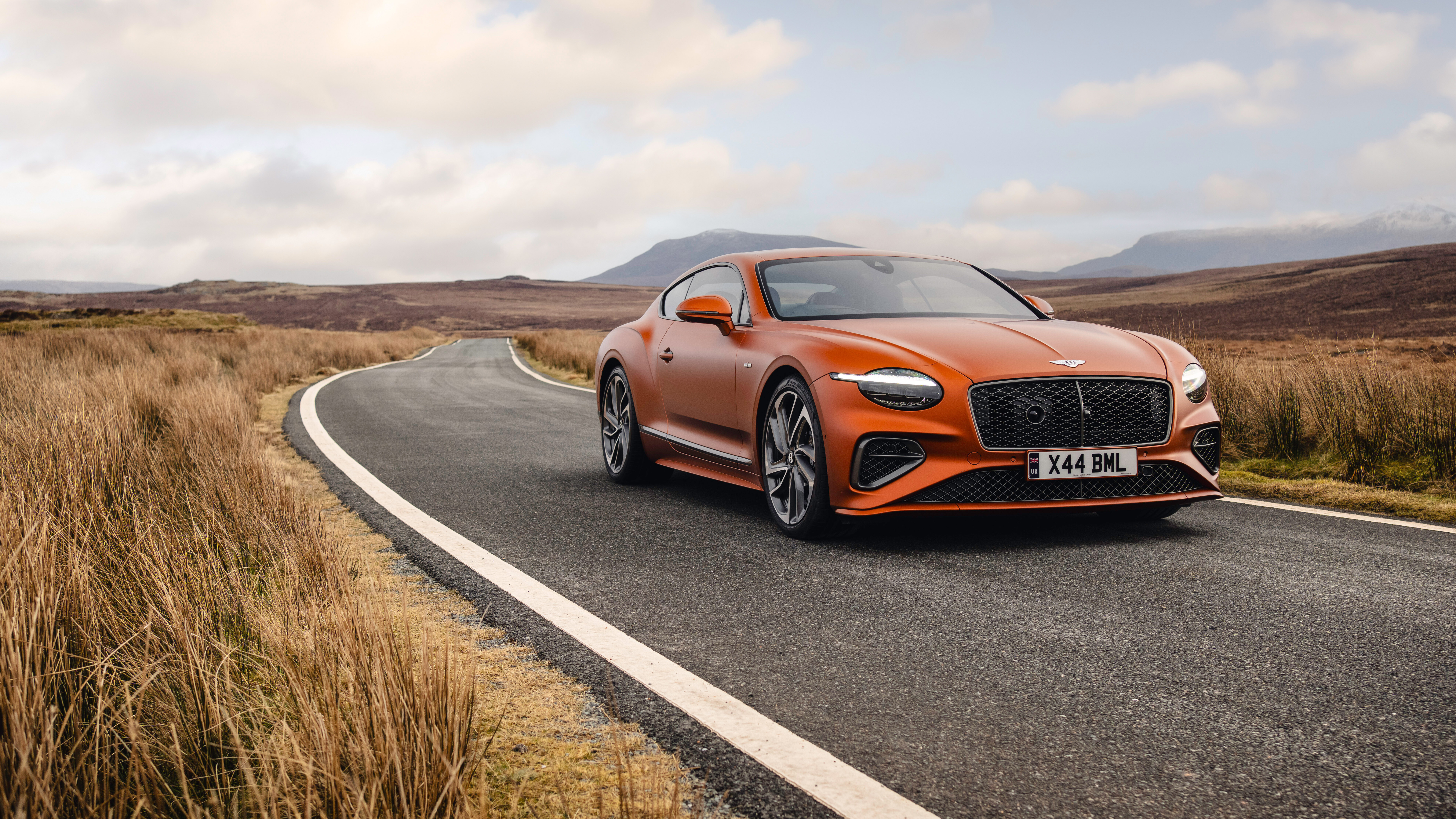 Яркий оранжевый Bentley Continental GT Speed, демонстрирующий свой роскошный дизайн и внушительный вид.