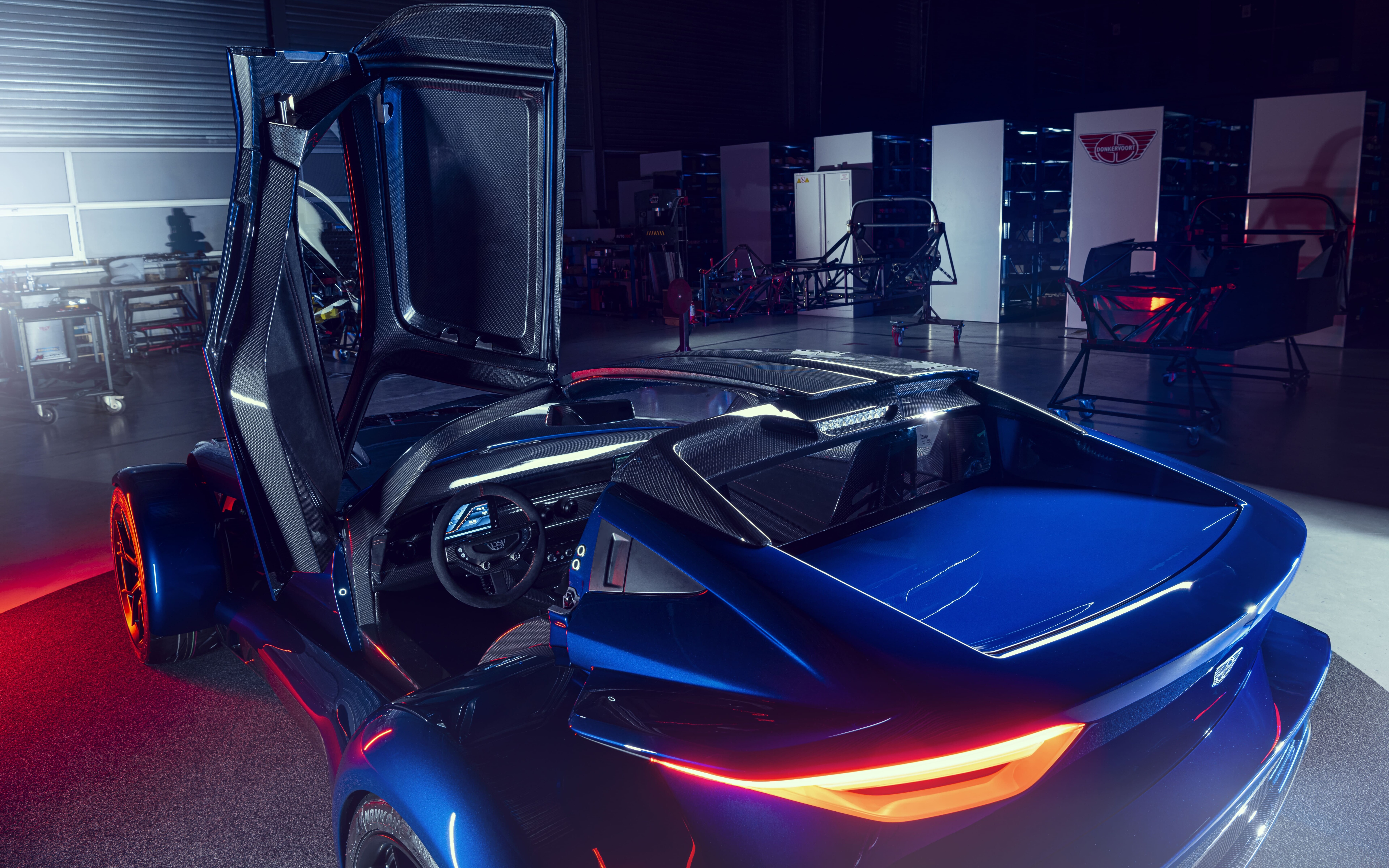 Элегантный спортивный автомобиль серебристого цвета с металлическим блеском, отражающий мягкий свет студийных софитов на тёмном фоне.